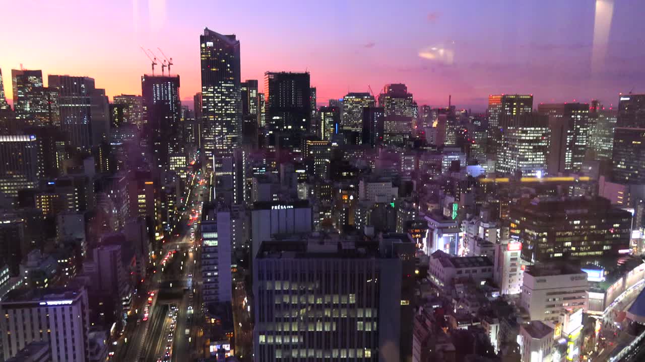 Purple and orange sunset over Tokyo with city lights and tall skyscraper buildings, 4K tilting up