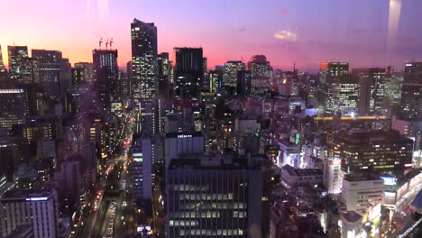 purple and orange sunset over tokyo with city lights and tall skyscraper buildings, 4k tilting up