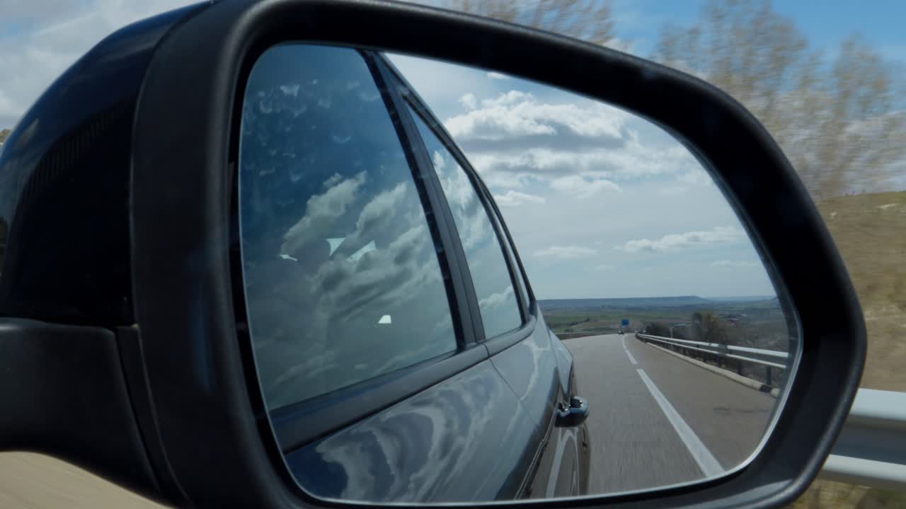 Vista di strada e cielo riflessi nello specchietto laterale dell'auto