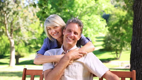 Mujer-Feliz-Abrazando-A-Su-Pareja-En-Un-Banco-Del-Parque