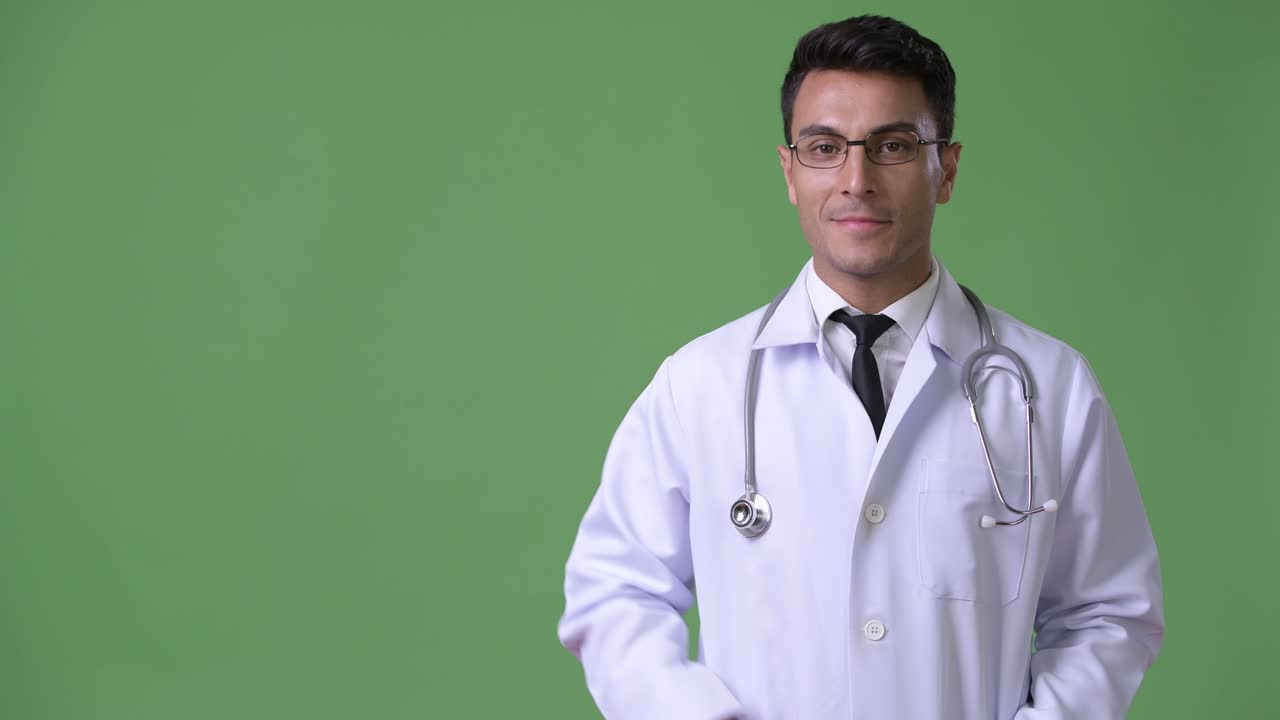 Dokter pria Hispanik muda yang tampan dengan latar belakang hijau.