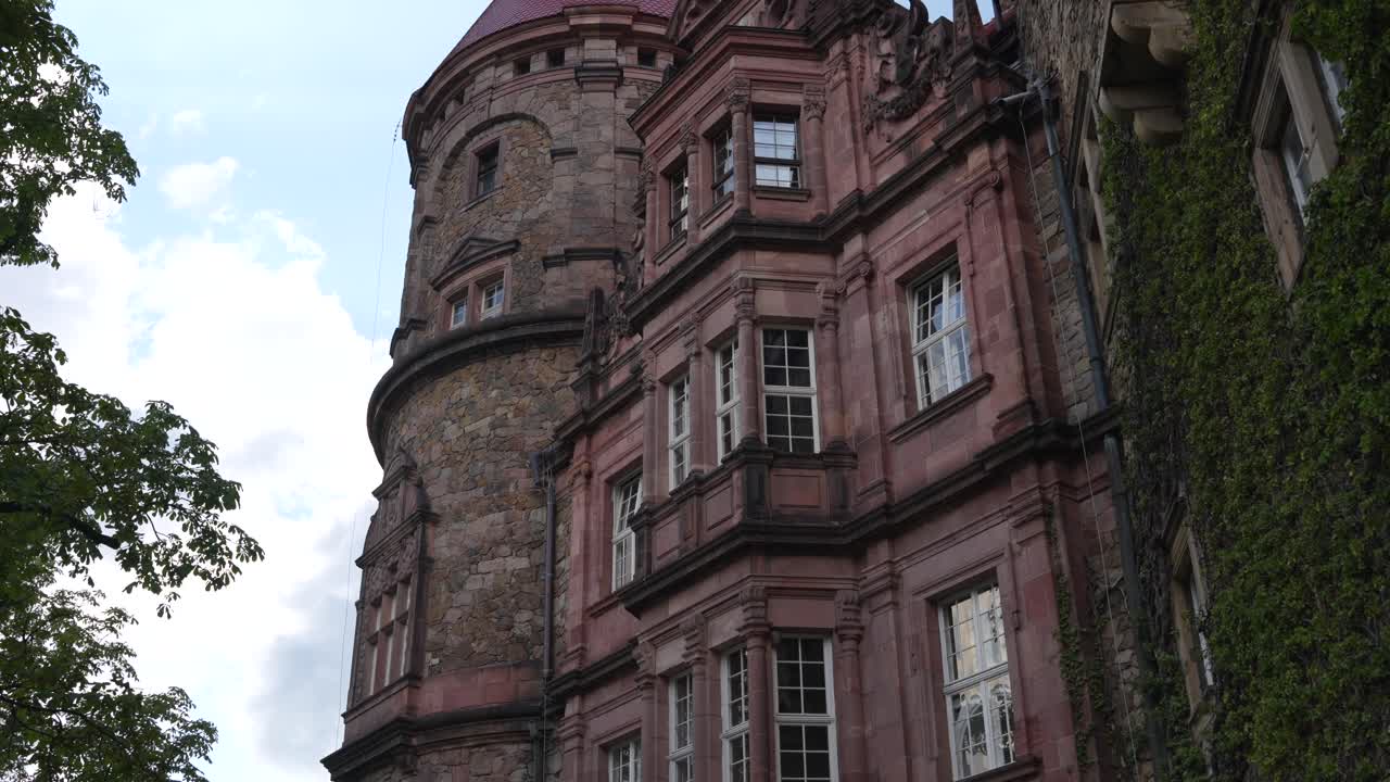 Historic facade of Ksiaz Castle with gothic architecture and vines on wall