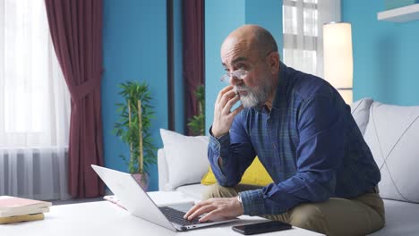 Elderly-man-is-using-laptop-in-a-focused-and-serious-manner.