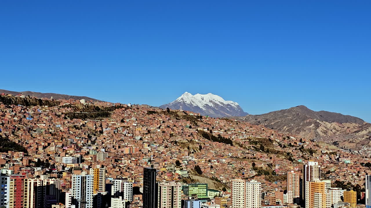 Beautiful view of La Paz city with colorful buildings and Illimani mountain in background, bright blue sky and urban mountain scenery of Bolivia