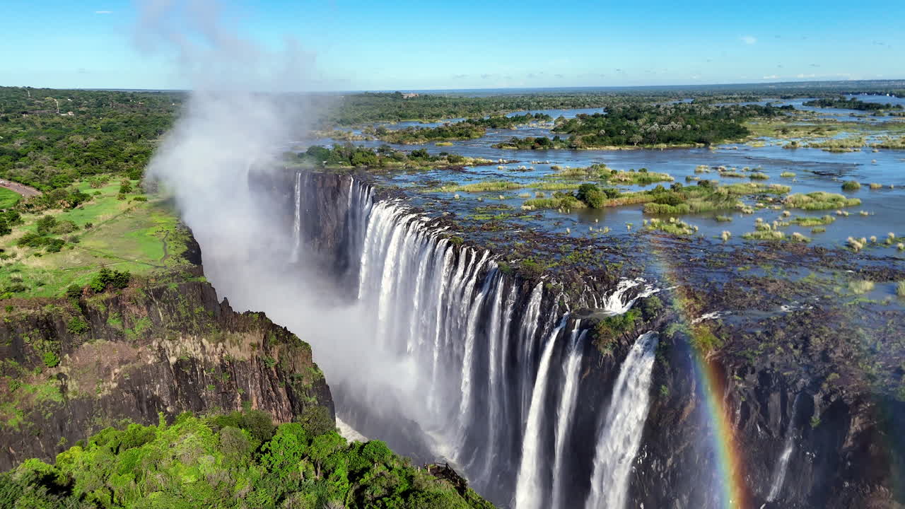 Aerial view of Victoria Falls with powerful waterfall plunging into gorge, mist rising above lush green forest, dramatic natural wonder and iconic travel destination in Africa