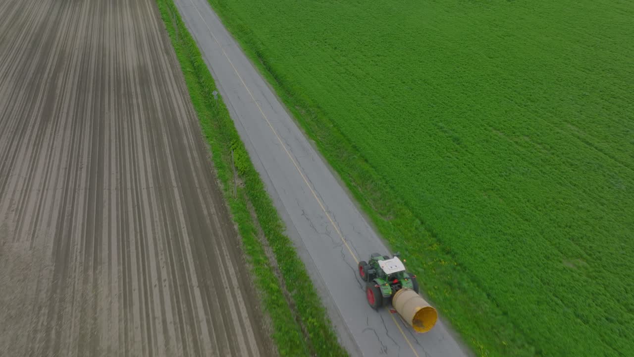 수확기 농장 트랙터가 들판을 가로질러 도로를 가로질러 운전하고 있습니다.