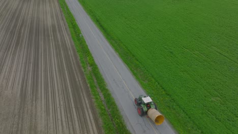 harvester farm tractor is driving across the road through the fields