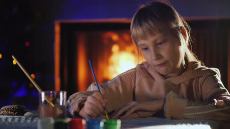 Girl-Paints-Near-The-Fireplace-And-Christmas-Tree