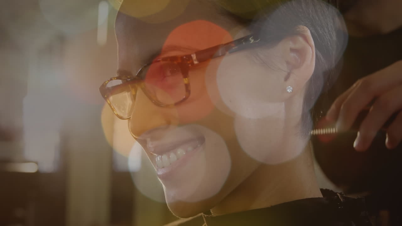 vista lateral de una mujer sonriendo mientras se le hace el cabello con efecto bokeh en primer plano