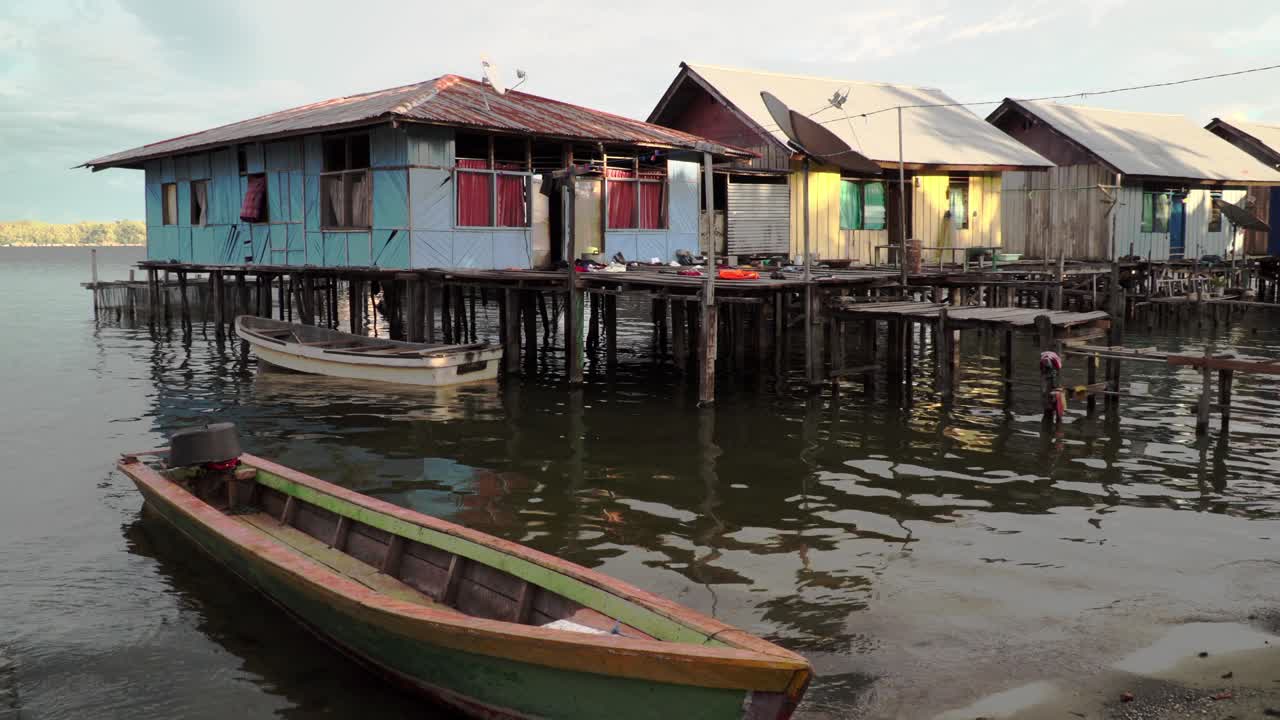 A wooden boat in front of colorful stilted houses at the water's edge