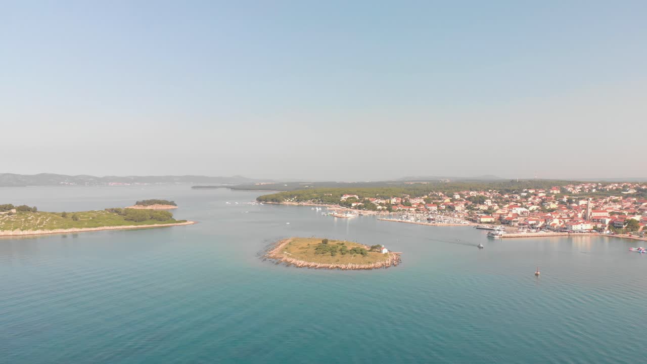 una imagen aérea de aspecto profesional del mar adriático cristalino en el mediterráneo, volando hacia una pequeña ciudad llamada pakostane, mostrando el hermoso paisaje terrestre y marítimo con islas y puerto deportivo
