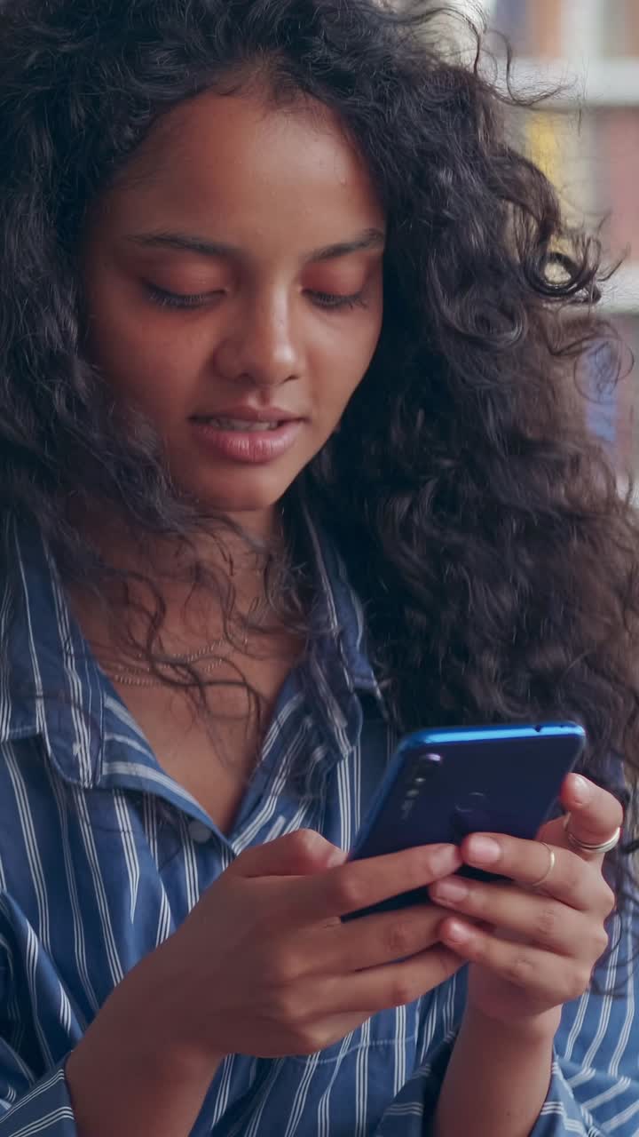 Young cute smiling indian woman uses smartphone typing status on social network