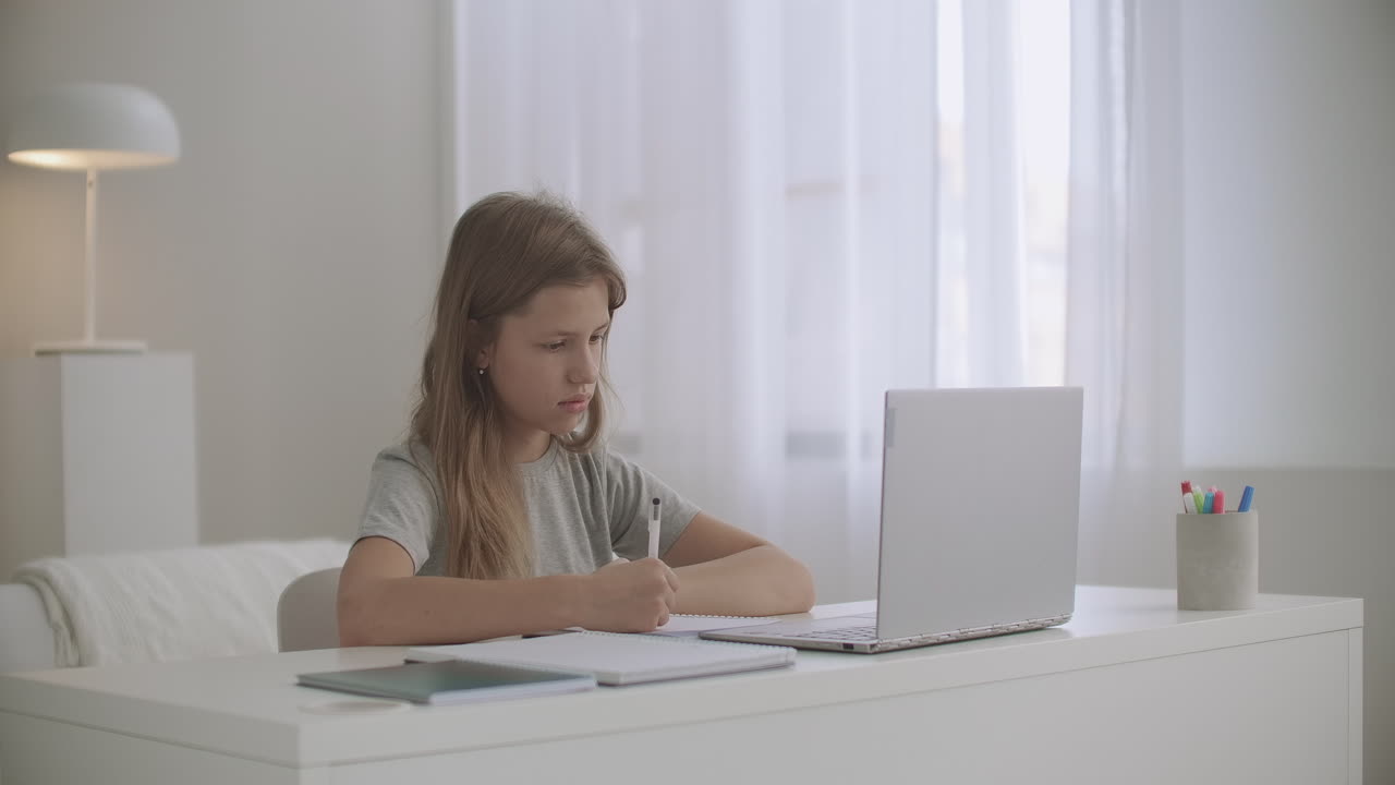 niña de escuela está aprendiendo en línea en casa viendo en la exhibición del cuaderno y escribiendo en el libro de copia aprendizaje electrónico y educación en casa en la pandemia de coronavirus
