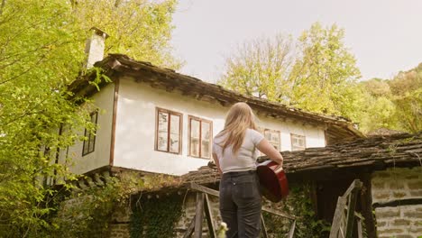 bela garota de campo toca guitarra acústica cena de aldeia rústica