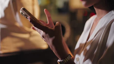mujer usando un teléfono inteligente en un café por la noche