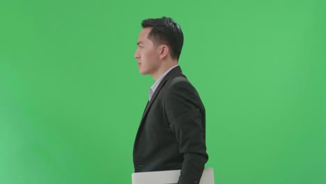 side view of asian business man holding book and document while walking on green screen chroma key