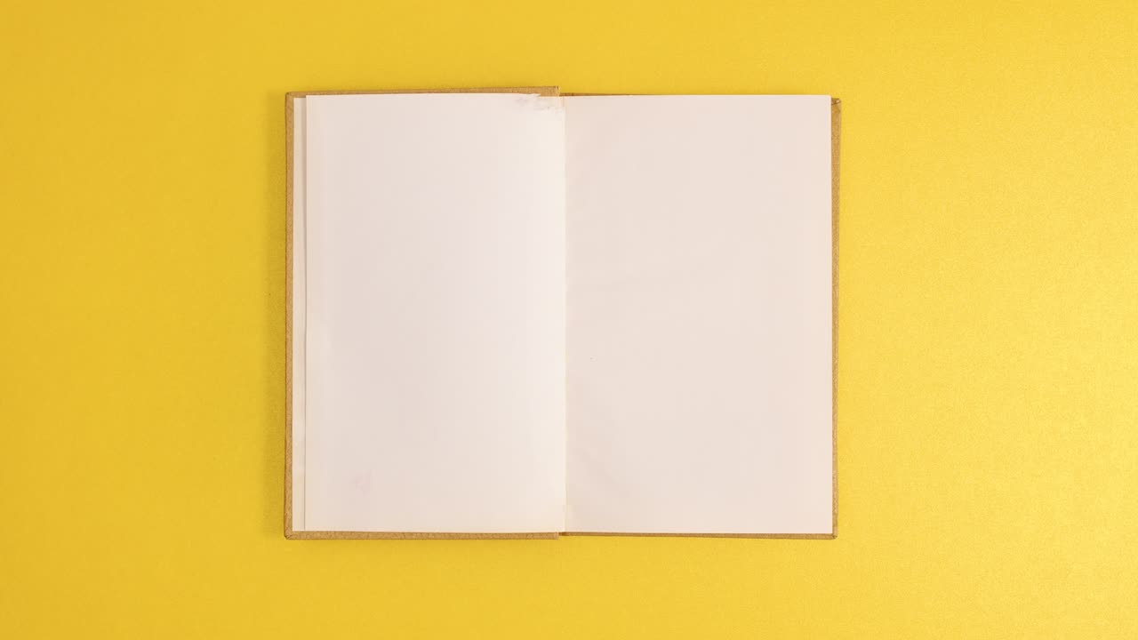 Golden vintage hardcover book appear and open with copy space on golden background. Stop motion flat lay