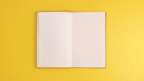 golden vintage hardcover book appear and open with copy space on golden background. stop motion flat lay