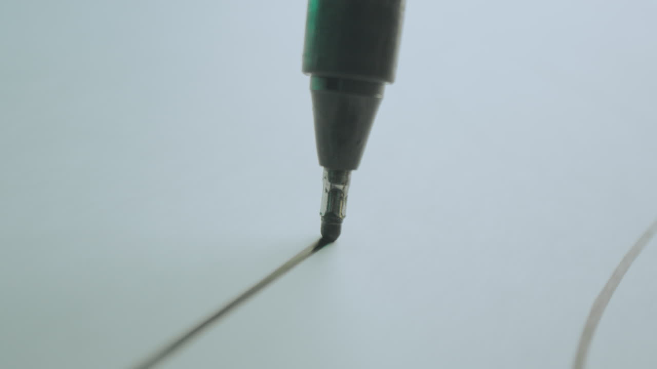 Close-up of a marker drawing lines on paper