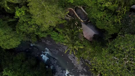 Drone-footage-highlighting-the-breathtaking-Tegenungan-Waterfall-in-Bali,-Indonesia,-featuring-the-picturesque-landscape-and-visitors-relishing-the-cool-waters