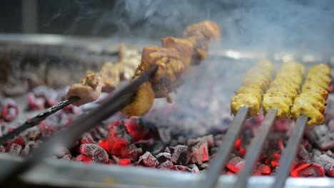 handheld, slow motion close up of smoky chicken kabab on a fiery charcoal hibachi grill