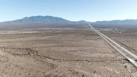 Toma-Aérea-A-Gran-Altura-Del-Desierto-De-Mojave-Con-La-Interestatal-15-En-El-Lado-Derecho-Que-Se-Extiende-Hasta-El-Horizonte