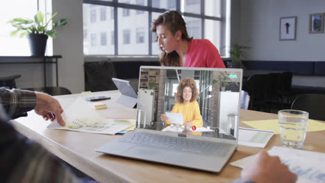 Caucasian-businessman-on-laptop-video-call-with-african-american-female-colleague-on-screen