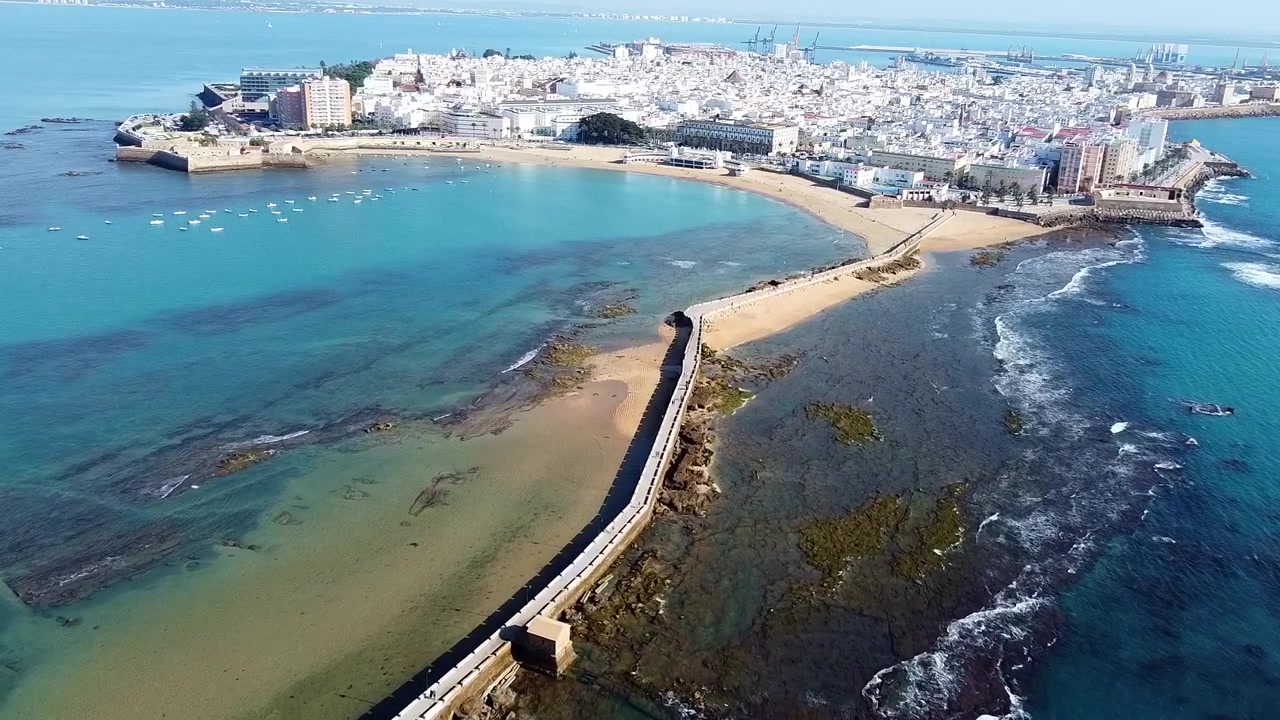 Spiaggia La Caleta. Cadice. Spagna. Vista aerea della spiaggia, del frangiflutti e delle barche da pesca ancorate in una cala di un mare turchese sorprendente.