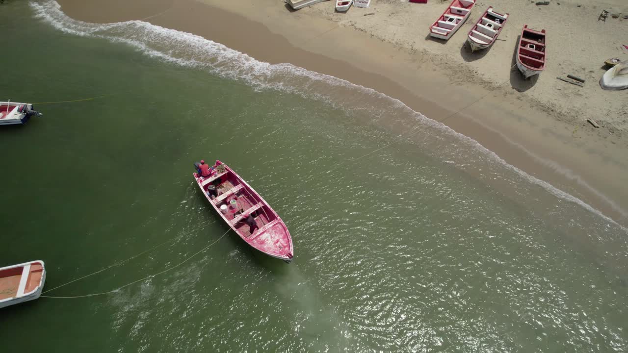 Drone shot fishermen leaving Osma beach onboard red small boat. survival skills sport fishing Venezuela,