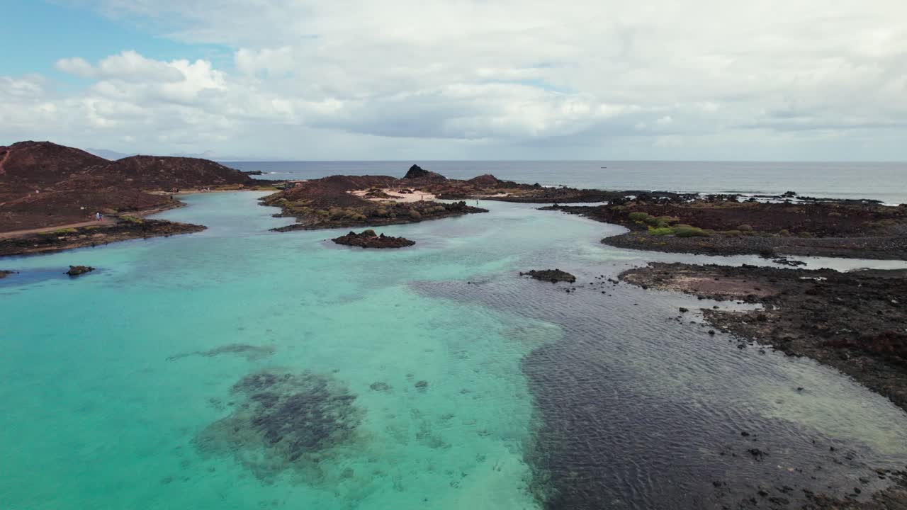 Turquoise waters, rocky coastlines, and volcanic terrain showcasing coastal beauty and serene landscapes. 4k aerial drone view of Puertito Isla de Lobos, Fuerteventura