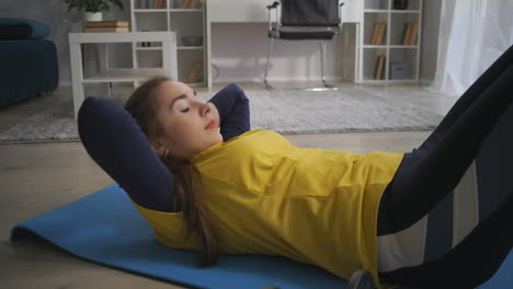 woman is doing exercises for abdominal muscles lifting torso lying on floor training at home alone sporty lifestyle