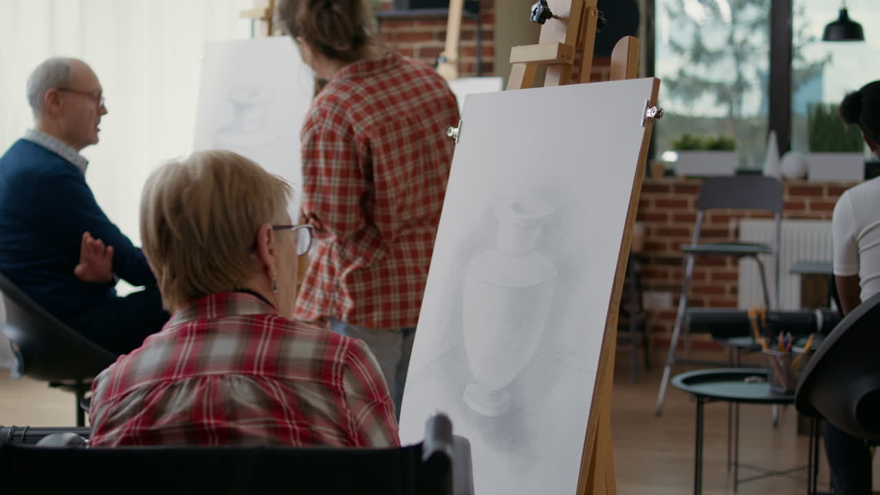 Elder woman with disability attending art class lesson with young artist