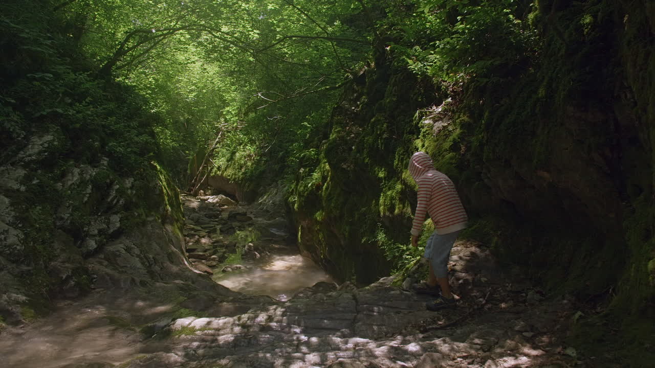 persona caminando a través de un cañón de arroyo de montaña