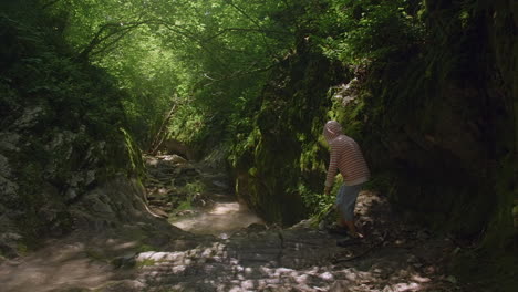 person hiking through a mountain stream canyon