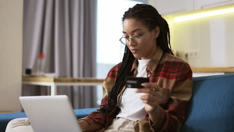 young african american holding credit card using laptop and buying online