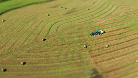 un tractor con un fabricante de balas de heno en el campo recién cortado haciendo balas de hena