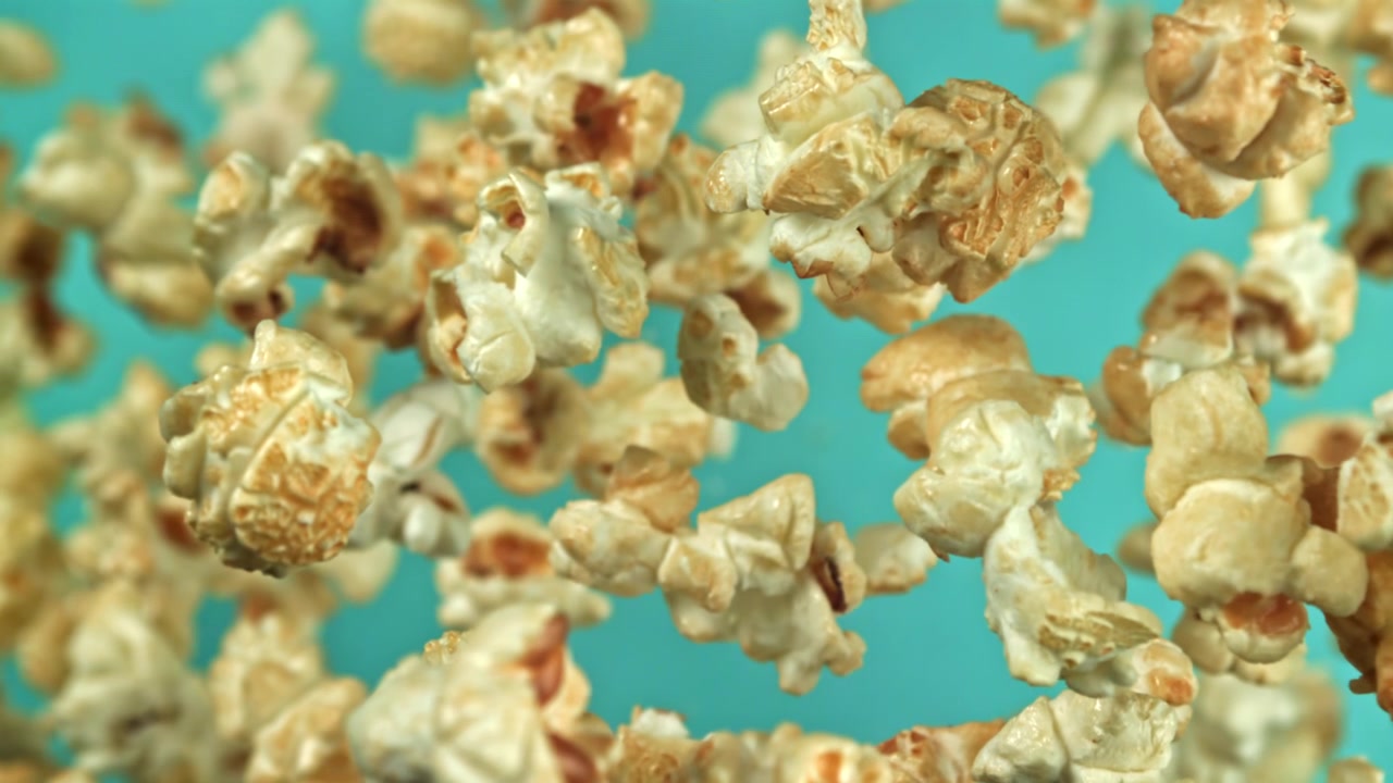 Golden Popcorn Kernels Floating Against a Teal Background