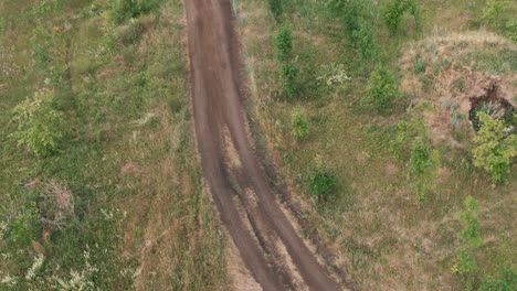 Aerial-View-Of-Two-Men-Riding-Motocross-On-A-Dirt-Road-In-The-Forest