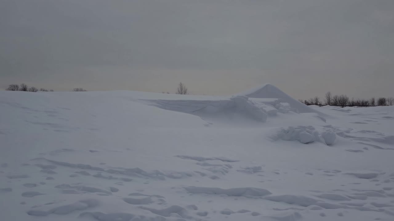 Wide-angle video captures a serene snow-covered landscape with gentle slopes and distant trees