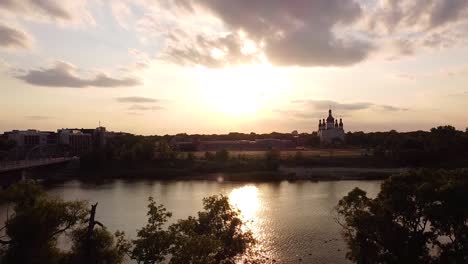 Crane-Down-Drone-Shot-Trees-Foreground-Church-Geese-River