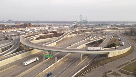 Cars-and-trucks-driving-on-I75-road-leading-to-Ambassador-bridge,-aerial-drone-view