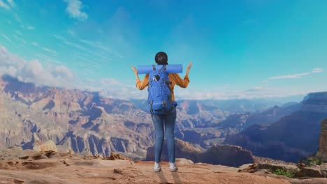 full body back view of a female hiker with mountaineering backpack spreading arms and looking the view around while traveling at the top of mountain