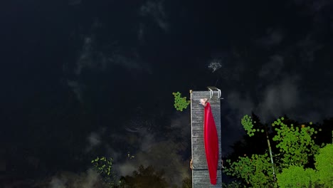 uhd top down view of a man catching and reeling in a fish from a dock in cottage country, ontario canada