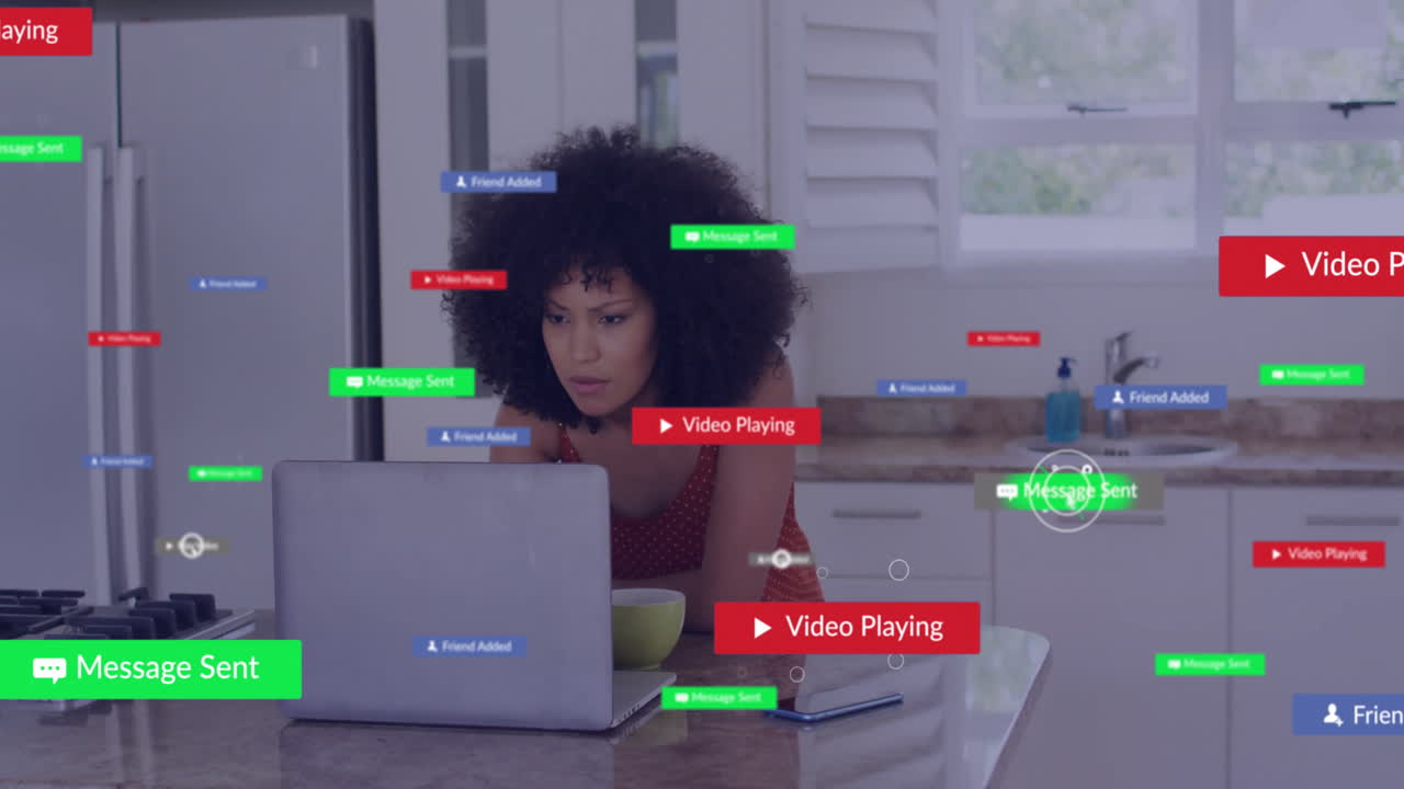 Using laptop in kitchen, woman viewing animation of social media notifications