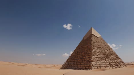 wide-angle video shot of a pyramid in a vast desert landscape under a clear blue sky