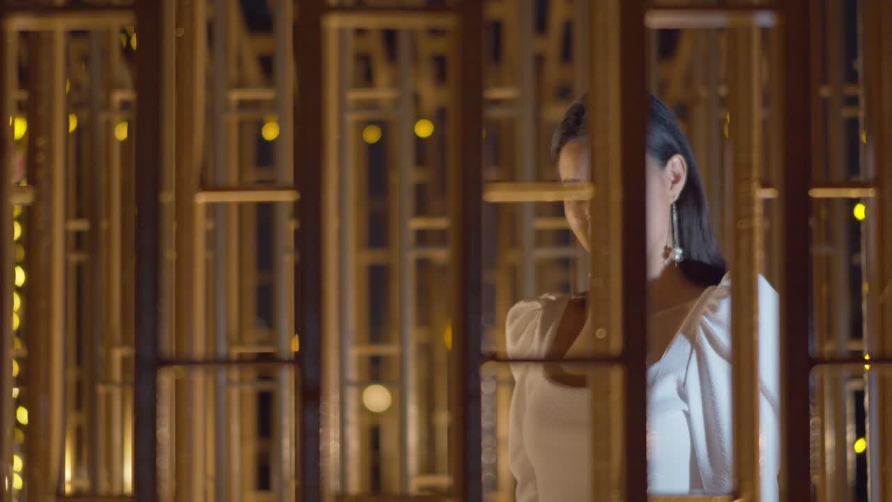 아름다운 아시아 여성이 카메라를 바라보며 멋진 표정과 미소를 지으며 창문의 벽을 따라 걷고 있습니다.