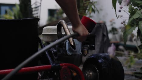 Close-up-shot-of-mechanic-washing-the-engine-of-a-DYI-go-kart-in-the-backyard