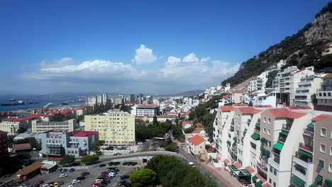 Drones-Aéreos-Vuelan-Alrededor-De-La-Ciudad-Costera-Casas-Turísticas-Antiguas-Mar-De-Alborán-Paisaje-Urbano-De-Gibraltar-Con-Horizonte-Soleado,-Autos-Estacionados-Alrededor-De-La-Vibrante-Ciudad-Costera-Mediterránea