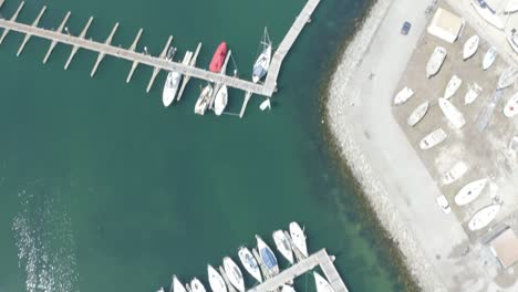 Drone-captures-midday-sun-illuminating-boats-at-a-dock-from-a-top-view-in-Portugal's-coastal-waters