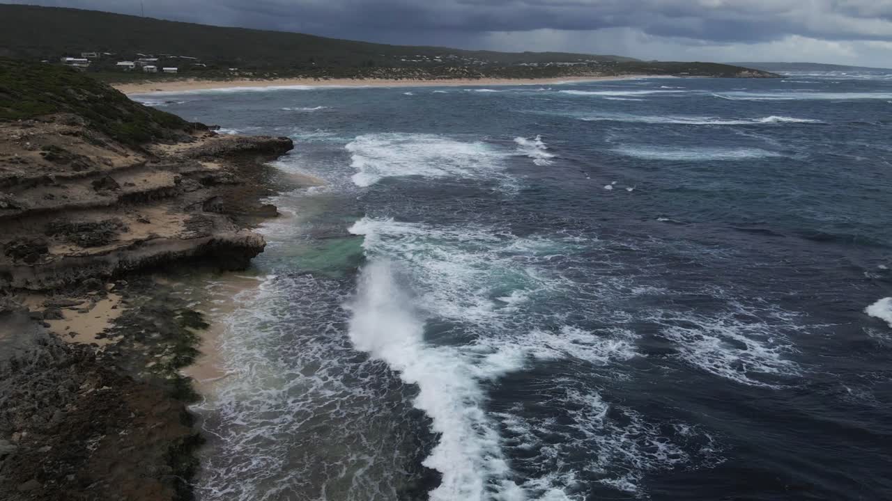 una toma dinámica de ángulo alto de la costa con fuertes olas de agua durante un buen tiempo